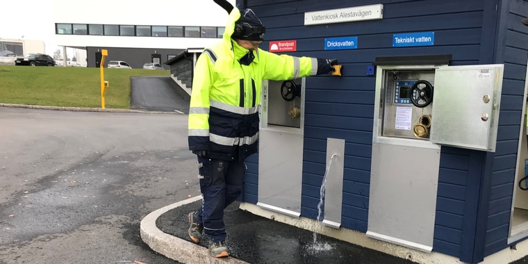 Personal med varseljacka står vid vattenkiosken vid Norrtäljes södra infart och visar var det finns dricksvatten.